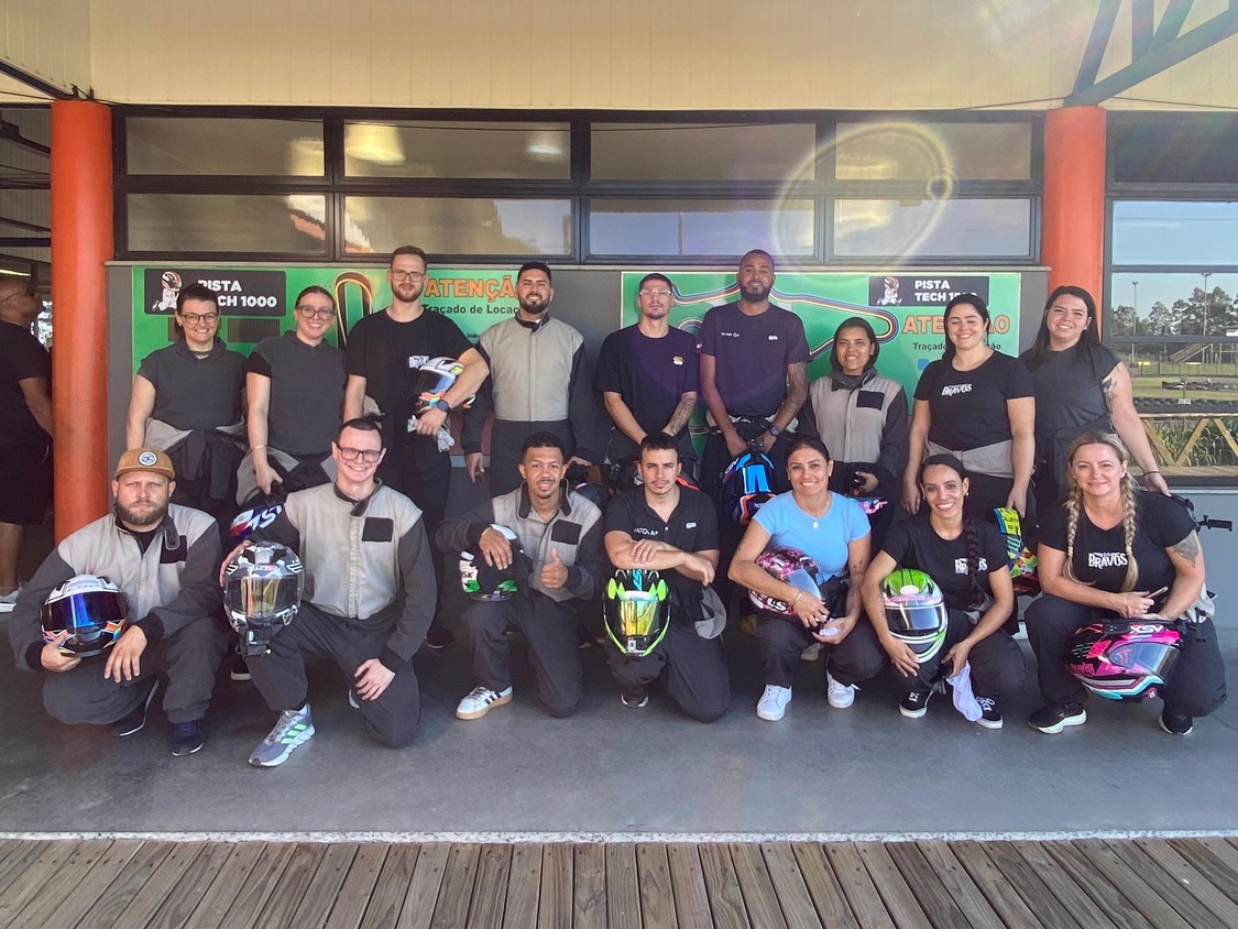 Integrantes do Los Bravos reunidos com macacões e capacetes em uma pista de kart