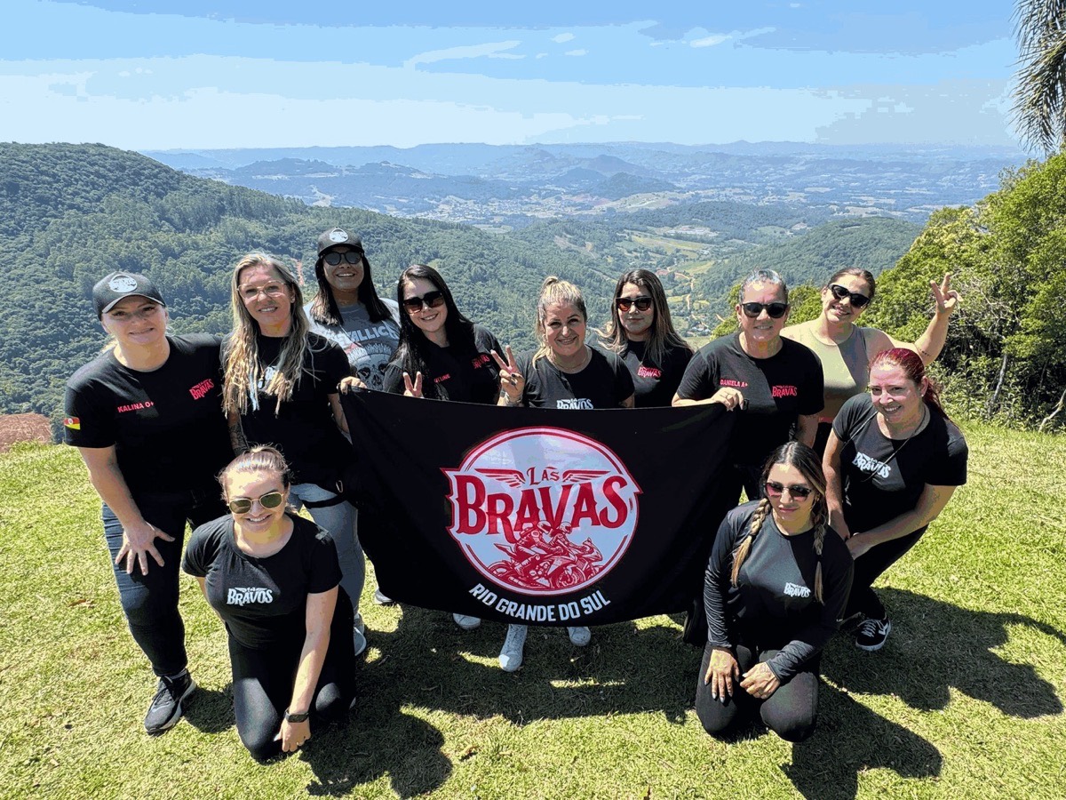Integrantes do Las Bravas com a bandeira do grupo em um mirante na serra gaúcha