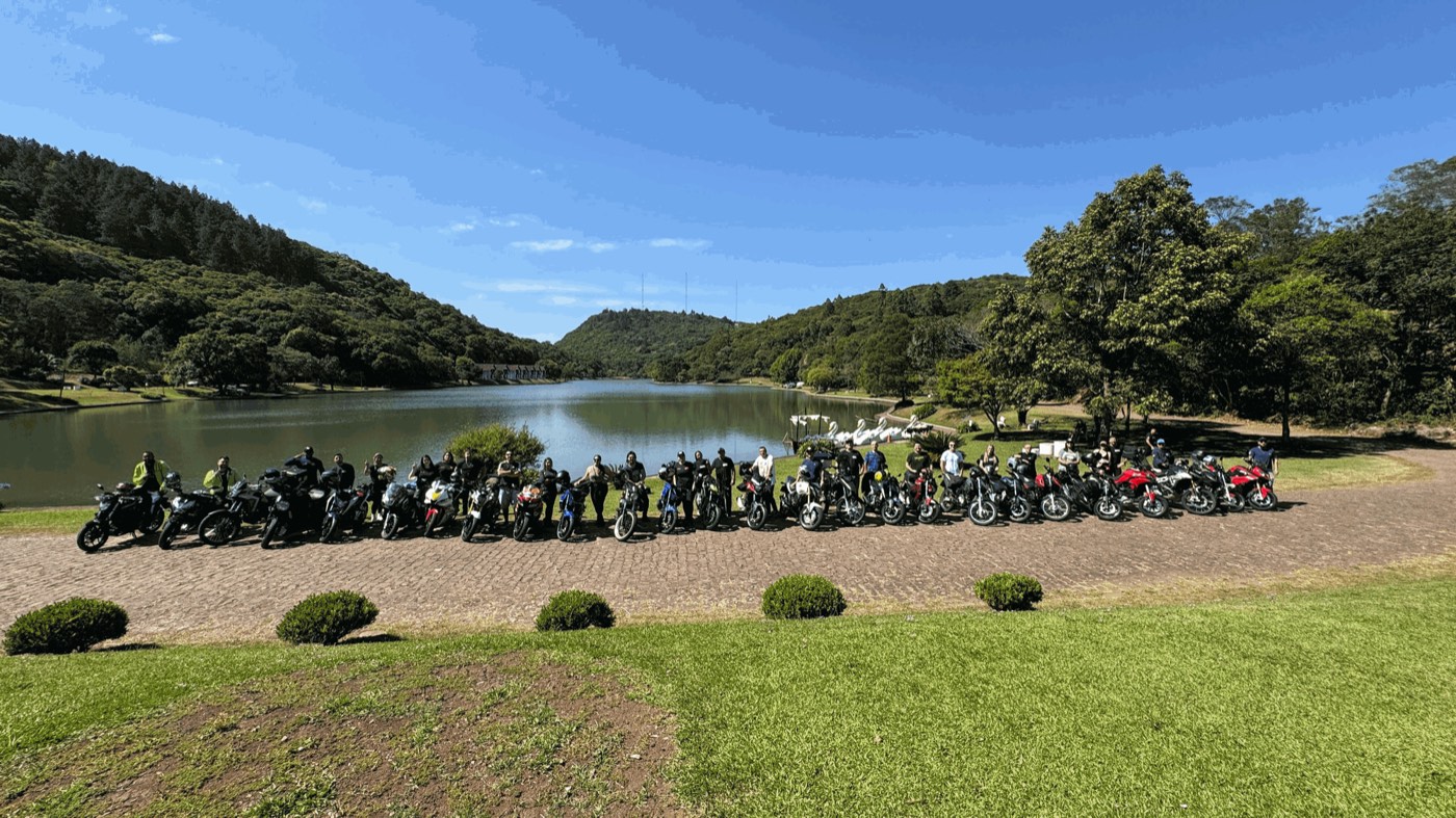 Motos do Los Bravos enfileiradas à beira de um lago cercado por morros na serra gaúcha